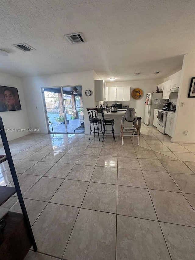 dining area featuring light tile patterned floors, a textured ceiling, and visible vents