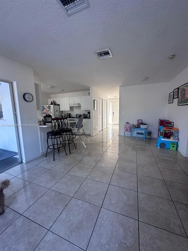 dining space with light tile patterned floors, visible vents, and a textured ceiling