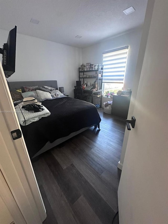 bedroom with a textured ceiling and dark wood finished floors