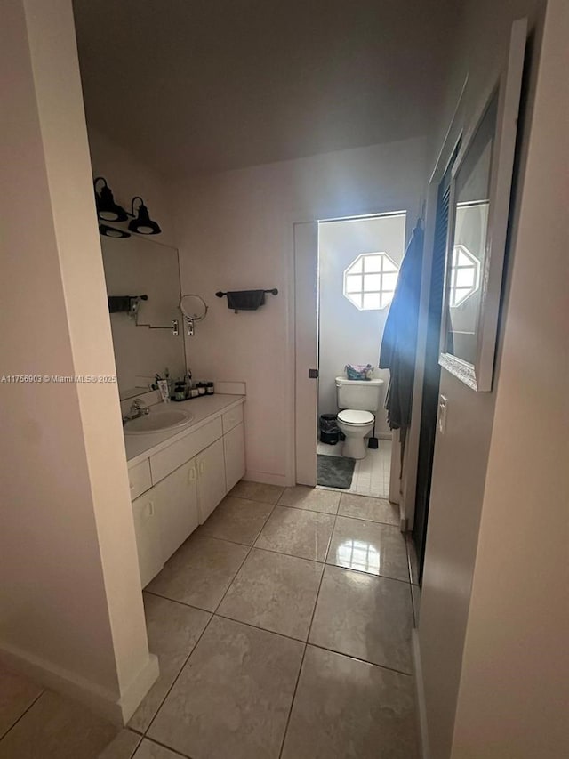 bathroom featuring tile patterned flooring, baseboards, vanity, and toilet