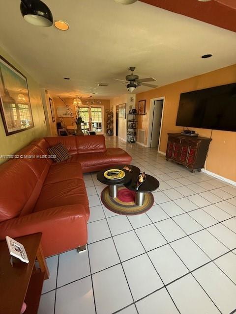 living area featuring ceiling fan, baseboards, and tile patterned floors