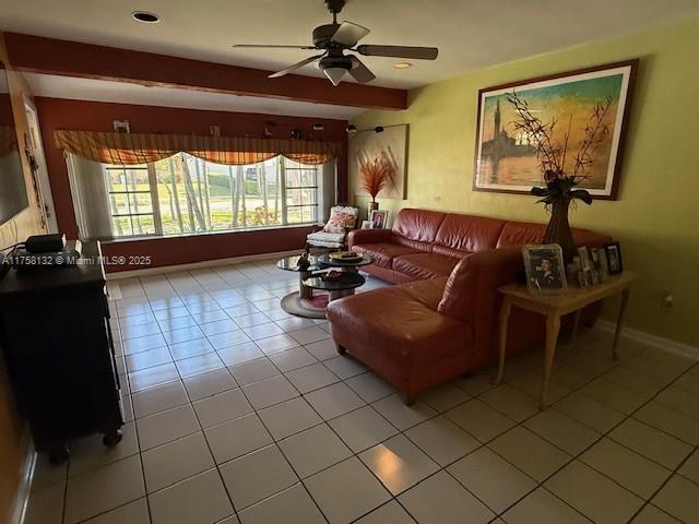 living room featuring light tile patterned floors, ceiling fan, beam ceiling, and baseboards