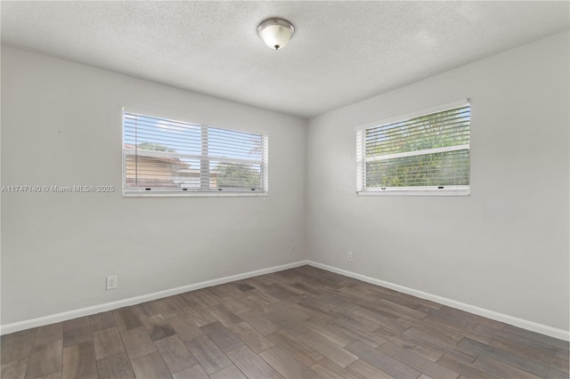 unfurnished room featuring a textured ceiling, baseboards, and wood finished floors