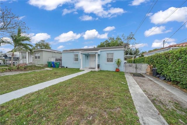 view of front of property with a front lawn, fence, a gate, and stucco siding