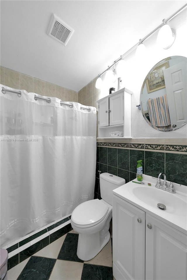 bathroom featuring visible vents, toilet, curtained shower, vanity, and tile walls