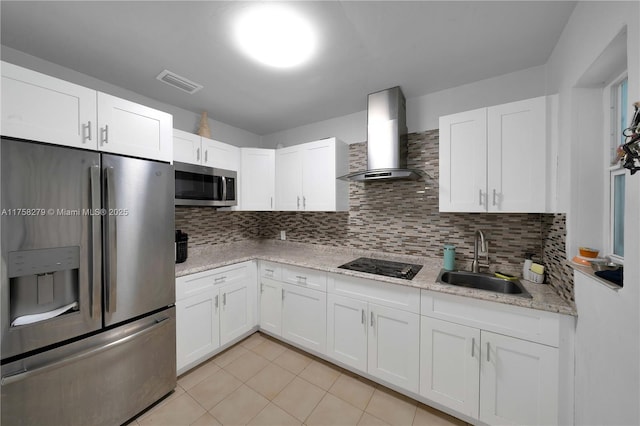 kitchen featuring a sink, visible vents, white cabinets, appliances with stainless steel finishes, and wall chimney range hood