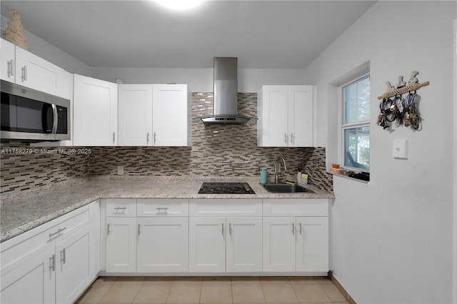 kitchen with tasteful backsplash, stainless steel microwave, black electric cooktop, wall chimney range hood, and a sink