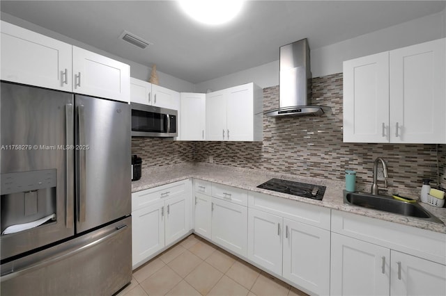 kitchen featuring visible vents, appliances with stainless steel finishes, white cabinetry, a sink, and wall chimney range hood