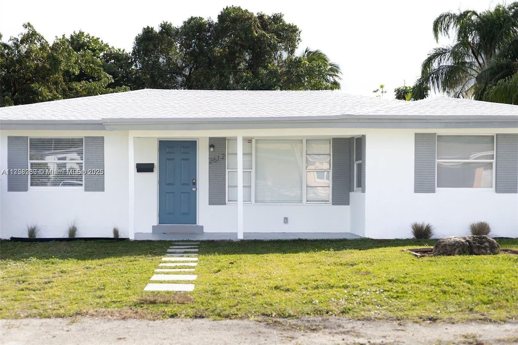 view of front facade with a front yard and roof with shingles