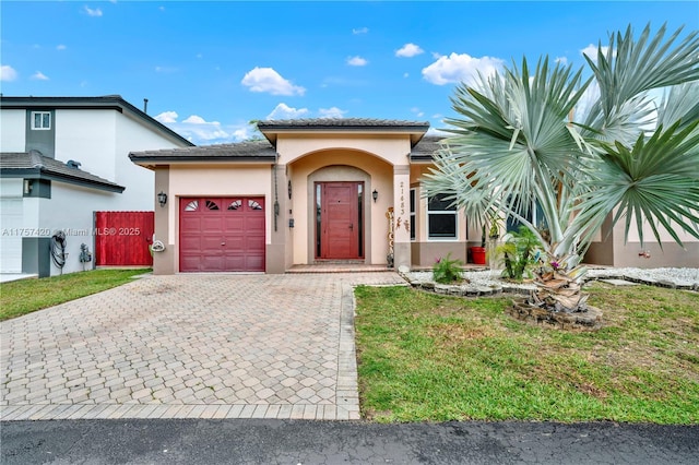 view of front of home with decorative driveway, stucco siding, an attached garage, fence, and a front lawn