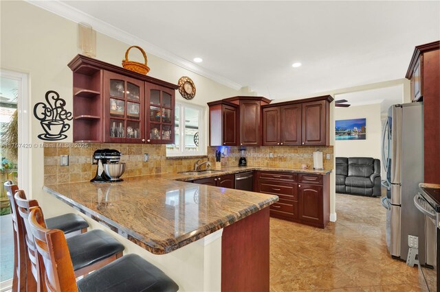 kitchen with stainless steel appliances, a peninsula, a sink, ornamental molding, and backsplash