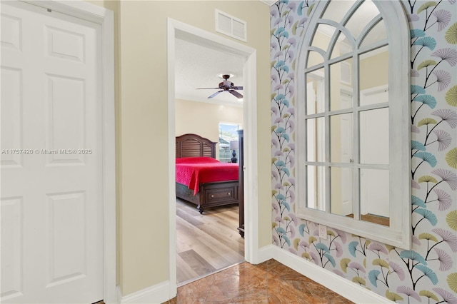 doorway with a ceiling fan, visible vents, and baseboards