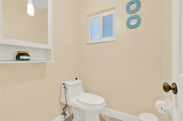 bathroom featuring toilet, tile patterned flooring, and baseboards