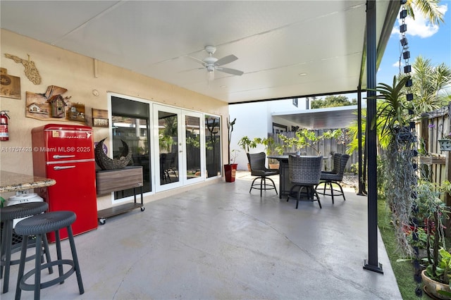 view of patio with outdoor dining space, fence, and ceiling fan