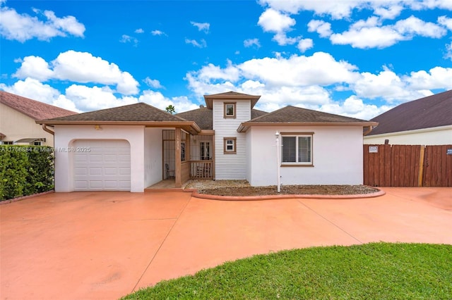 view of front of property featuring concrete driveway, fence, an attached garage, and stucco siding