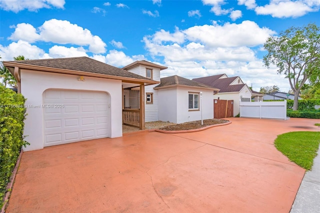 view of front of home with concrete driveway, an attached garage, fence, and stucco siding