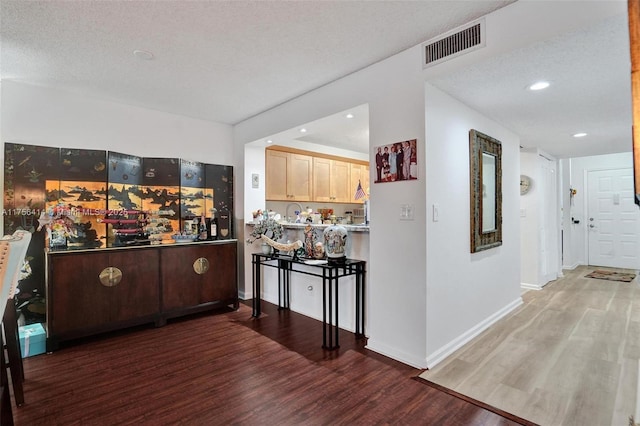 kitchen with light brown cabinetry, wood finished floors, visible vents, and baseboards