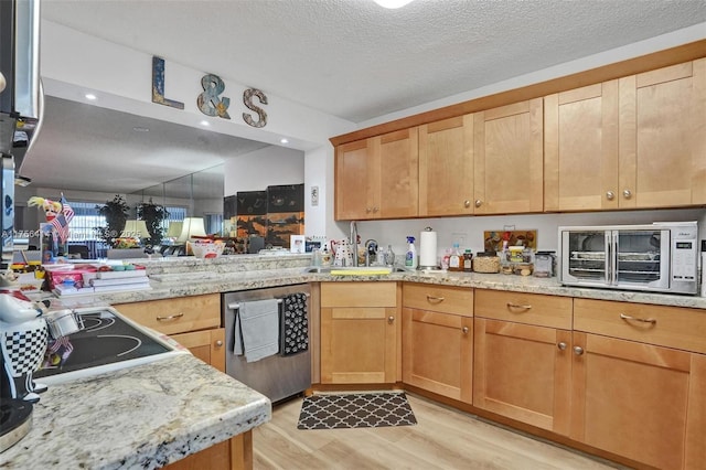 kitchen featuring a textured ceiling, light stone counters, a sink, dishwasher, and light wood finished floors