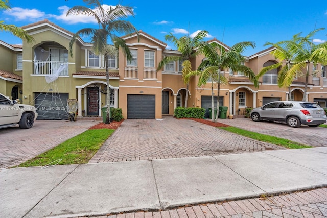 multi unit property with a garage, driveway, a tiled roof, and stucco siding