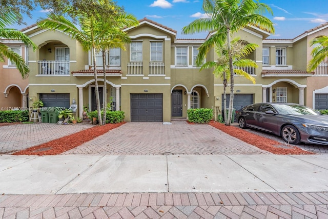 view of property featuring decorative driveway, an attached garage, and stucco siding