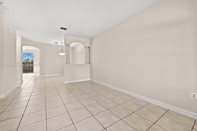 spare room featuring arched walkways, visible vents, and baseboards