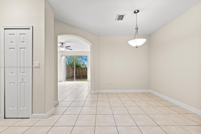 unfurnished room featuring arched walkways, ceiling fan, light tile patterned floors, visible vents, and baseboards