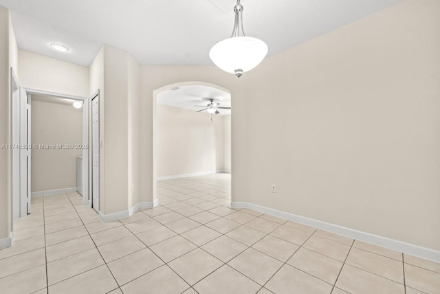 unfurnished dining area featuring light tile patterned floors, ceiling fan, arched walkways, and baseboards