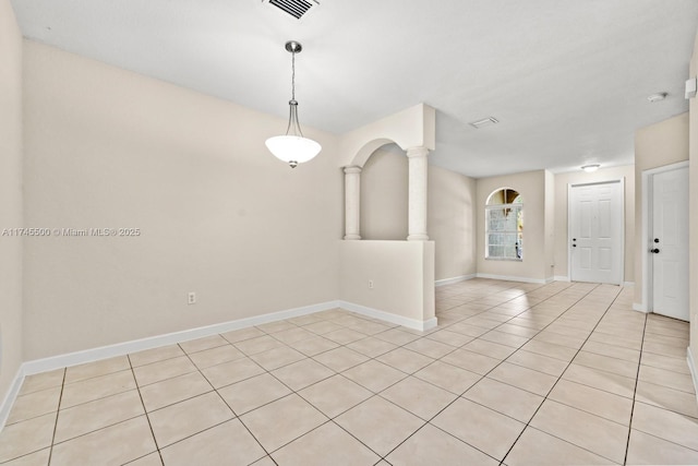 empty room with visible vents, light tile patterned floors, decorative columns, and baseboards