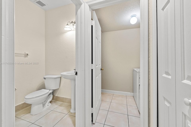 bathroom with visible vents, toilet, washing machine and clothes dryer, tile patterned flooring, and a textured ceiling