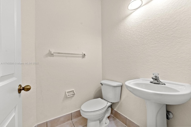 bathroom with toilet, baseboards, a sink, and tile patterned floors