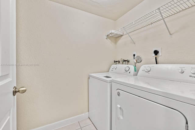 washroom with laundry area, light tile patterned floors, baseboards, and separate washer and dryer