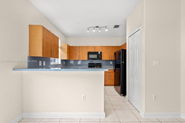 kitchen featuring brown cabinets, a peninsula, black appliances, and light tile patterned floors