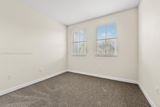 unfurnished room with carpet and baseboards