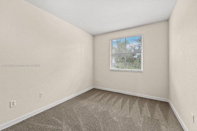 spare room featuring carpet floors and baseboards