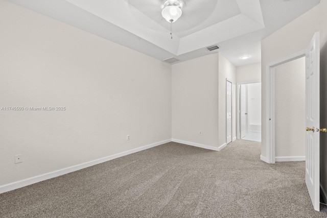 unfurnished room featuring carpet floors, baseboards, visible vents, and a raised ceiling