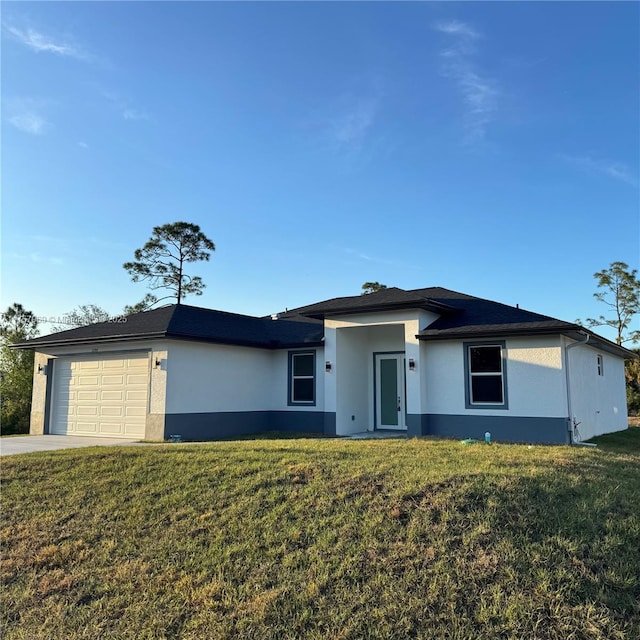 view of front of property featuring a garage, driveway, a front yard, and stucco siding