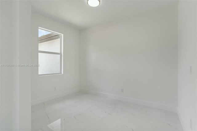 unfurnished room with marble finish floor and baseboards