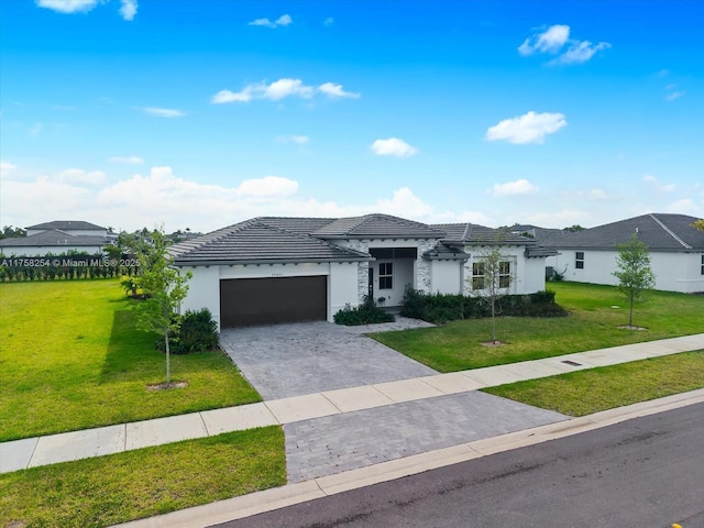 view of front of home featuring a garage, decorative driveway, a tile roof, and a front lawn