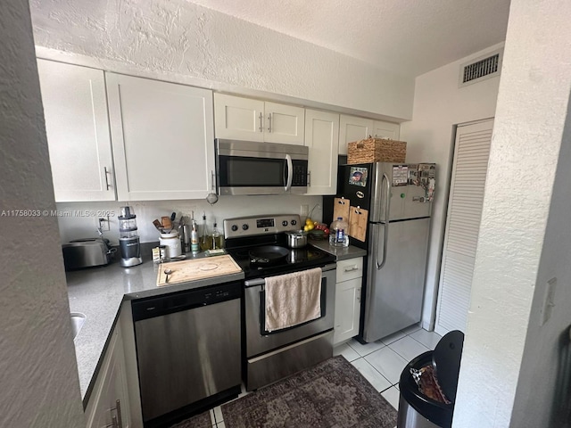 kitchen featuring visible vents, appliances with stainless steel finishes, a textured ceiling, white cabinetry, and light tile patterned flooring