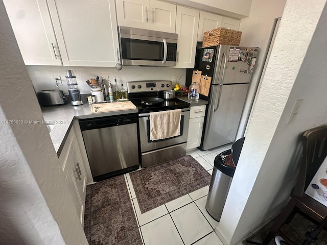 kitchen featuring appliances with stainless steel finishes, white cabinets, and light tile patterned flooring