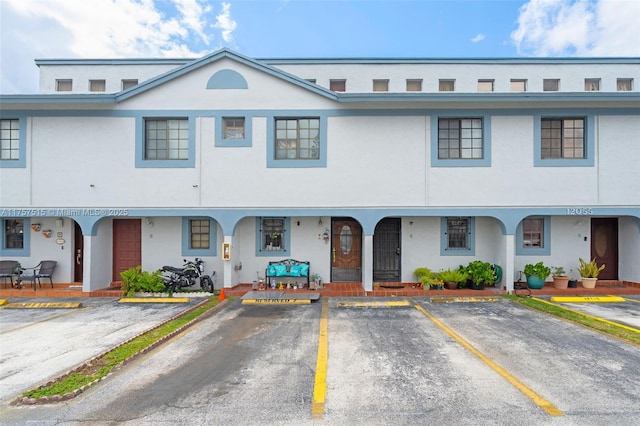 view of front of property featuring covered porch, uncovered parking, and stucco siding