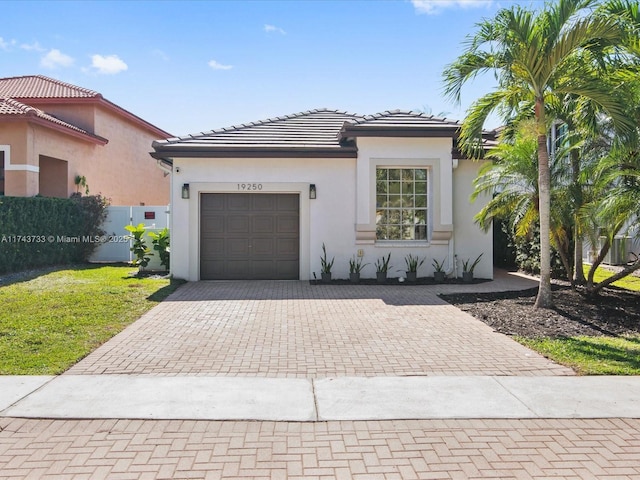 view of front of property featuring stucco siding, a tile roof, an attached garage, decorative driveway, and a front yard