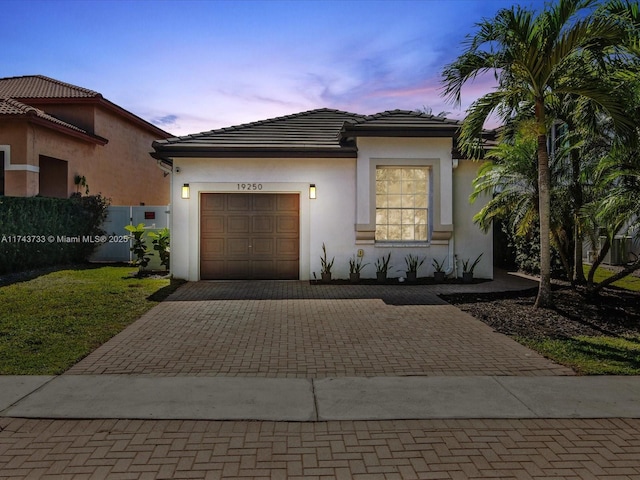 view of front of house with a garage, a tile roof, decorative driveway, and stucco siding