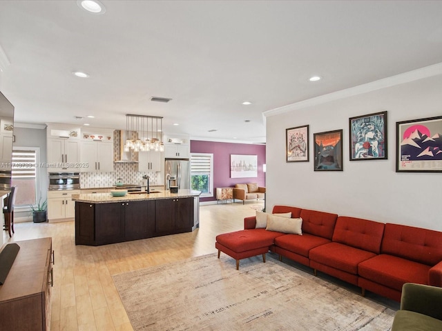 living room with light wood finished floors, ornamental molding, visible vents, and recessed lighting