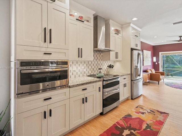 kitchen featuring tasteful backsplash, visible vents, light wood-style flooring, appliances with stainless steel finishes, and wall chimney exhaust hood