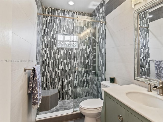 full bath featuring a stall shower, vanity, toilet, and tile walls