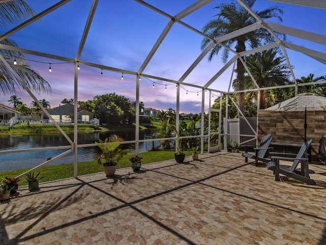 view of patio with glass enclosure and a water view