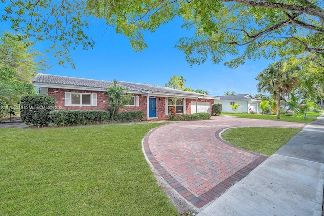 single story home featuring brick siding, a tiled roof, decorative driveway, and a front yard