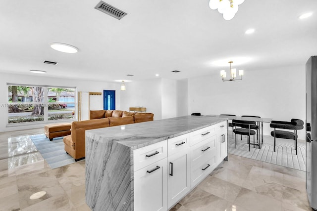 kitchen featuring marble finish floor, light stone counters, visible vents, and white cabinetry