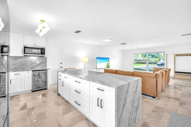 kitchen featuring wine cooler, stainless steel microwave, visible vents, and decorative backsplash